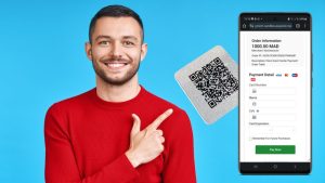 Un homme souriant pointant du doigt un QR Code et un smartphone affichant la page de paiement